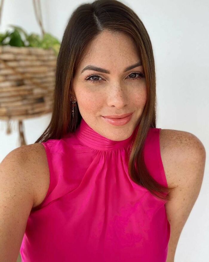 Miss Universe winner smiling in a bright pink sleeveless top, posing for a stunning close-up portrait photo.