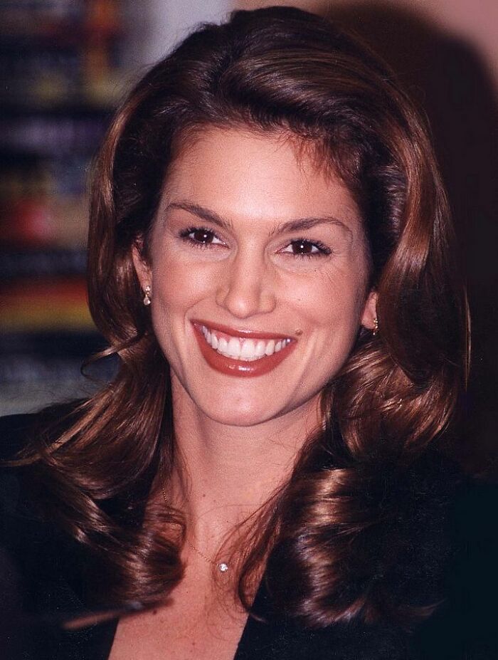Close-up of a smiling woman with styled brown hair showcasing changing beauty standards in history photos.