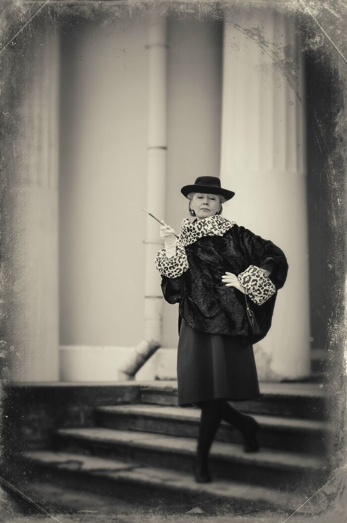 Woman in vintage cosplay outfit posing confidently on outdoor stairs, showcasing incredible cosplay style and elegance.