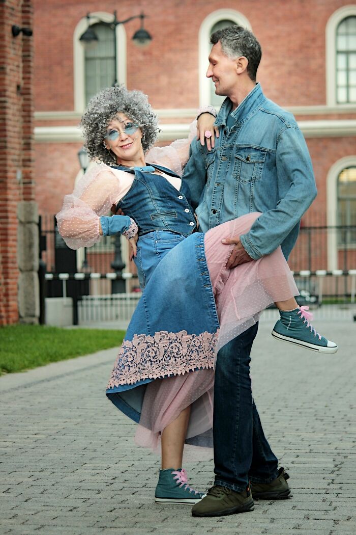 Woman surprising people with her incredible cosplays, wearing colorful denim and pink outfit with curly gray wig outdoors.