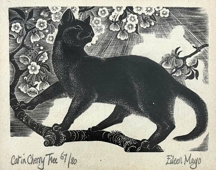 Vintage black cat perched on a cherry tree branch surrounded by blossoms, showcasing classic vintage cat artwork.