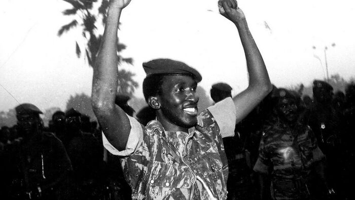 Black and white photo of a joyful soldier raising arms, symbolizing common folk's impact on society and history moments.