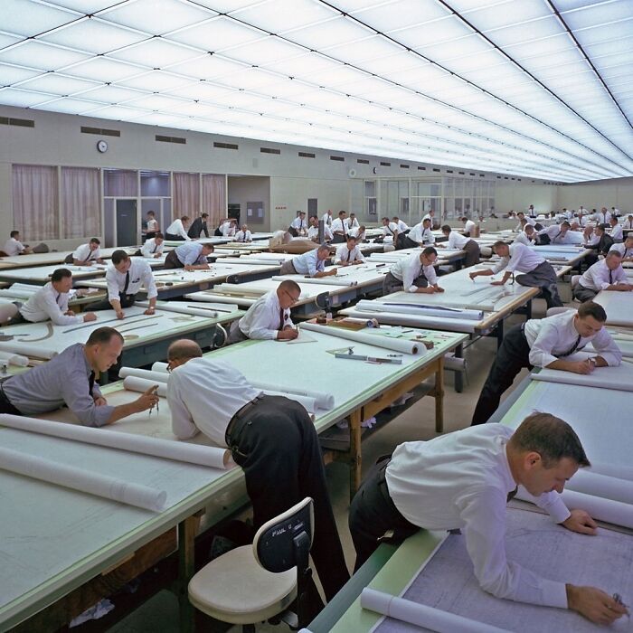 Men working intently on large drafting tables in a spacious room from a historical photo with an interesting backstory.