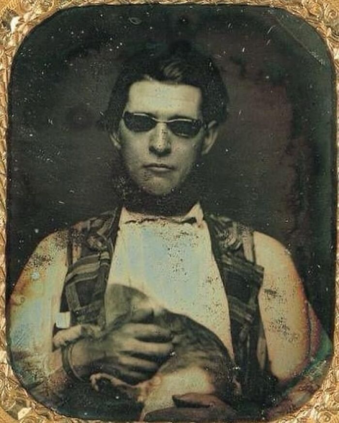 Vintage historical photo of a man wearing dark glasses and holding a cat, showcasing rare historical moments.