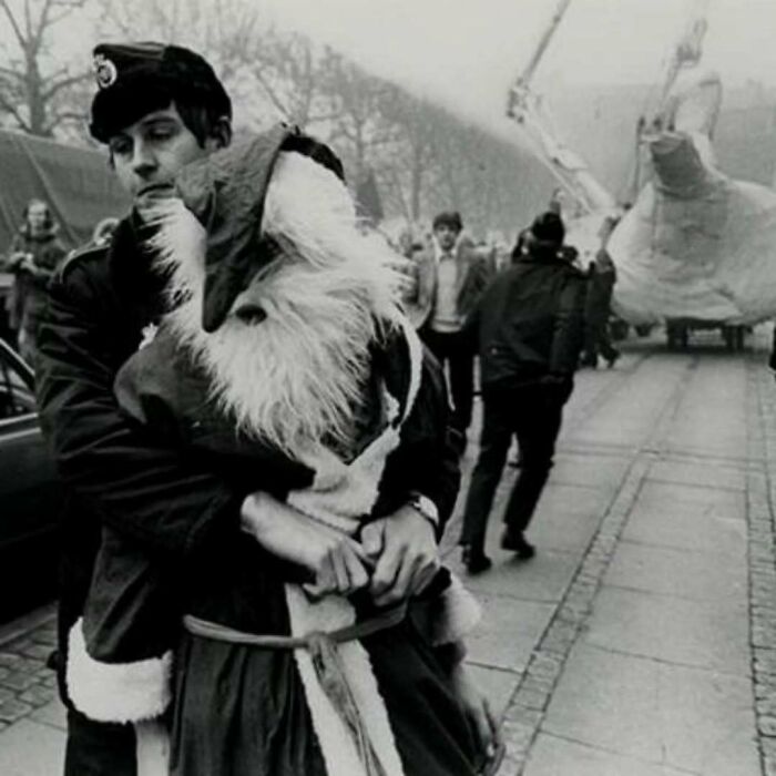 Police officer restraining a person dressed as Santa Claus during a public event, showing common folk making a mark in history.