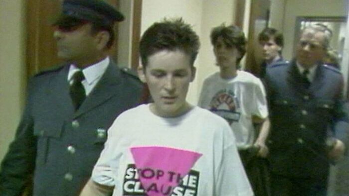 Young common folk wearing a protest t-shirt escorted by officers, illustrating times ordinary people made a huge mark in society.