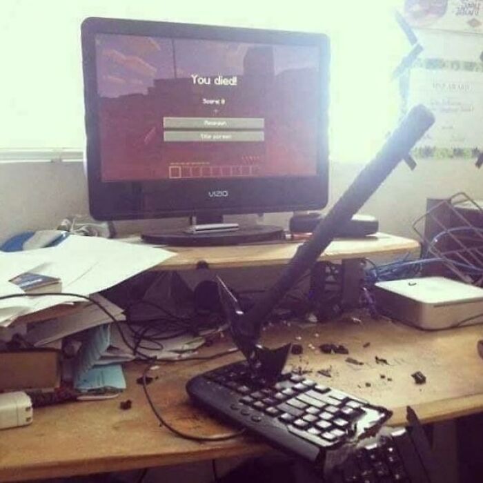 A cursed image showing a broken keyboard with an axe in it and a computer screen displaying a game over message.