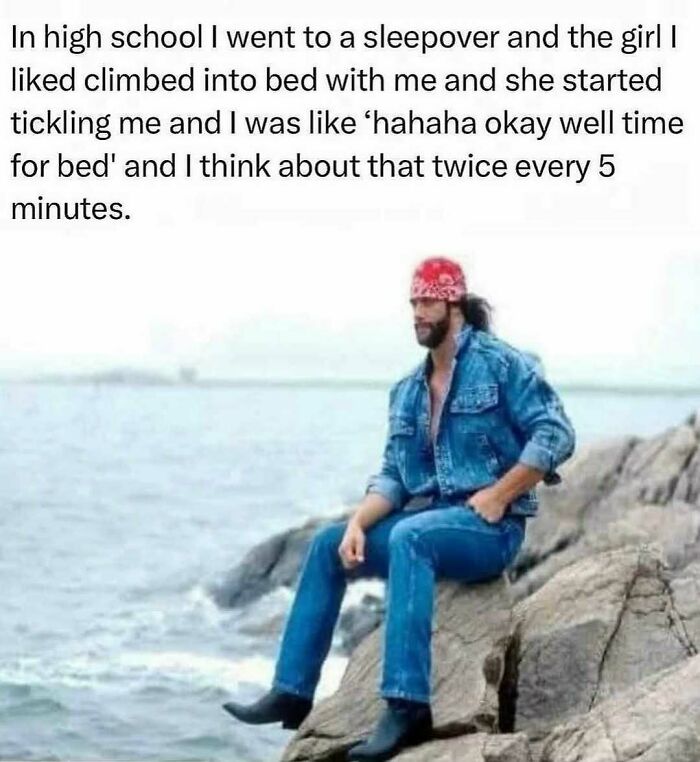 Man in denim jacket and bandana sitting on rocks by the sea, reflecting thoughtfully, capturing random memes chaos and fun.