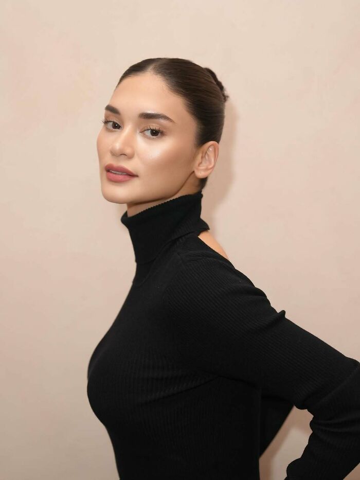 Miss Universe winner posing in a black turtleneck, showcasing elegance and grace in a stunning portrait photo.