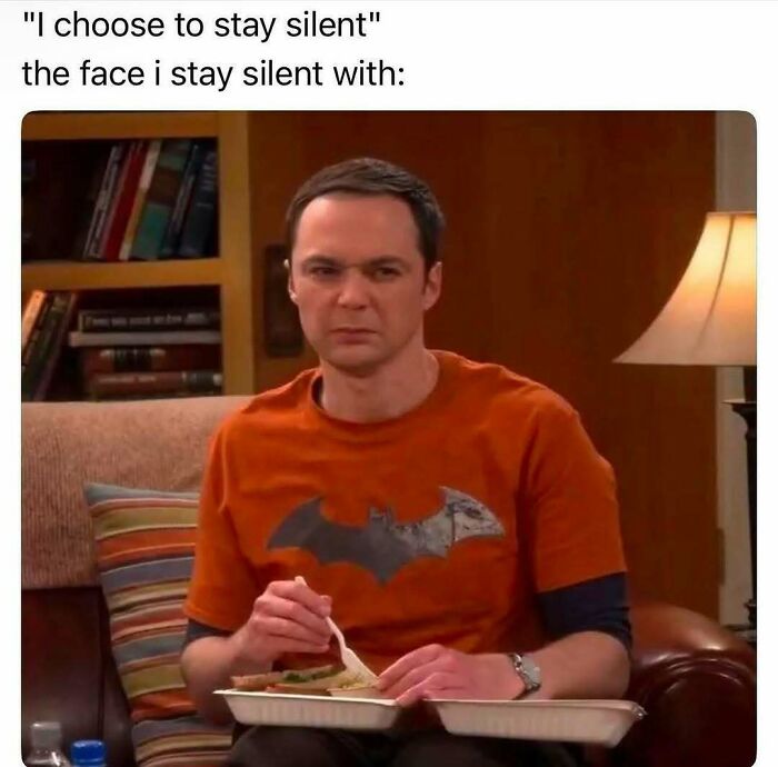 Man in orange shirt sitting on sofa with a skeptical expression, representing introvert-worthy memes about staying silent.