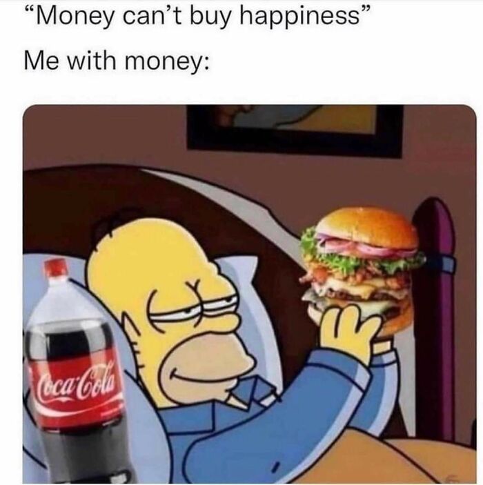 Homer Simpson in bed smiling while holding a burger and a bottle of Coca-Cola in a funny meme about money and happiness.