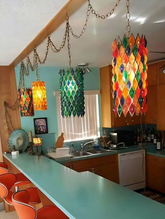 Vintage colorful hanging lights and retro kitchen with turquoise counter and orange chairs in June Cleavers vintage closet style.