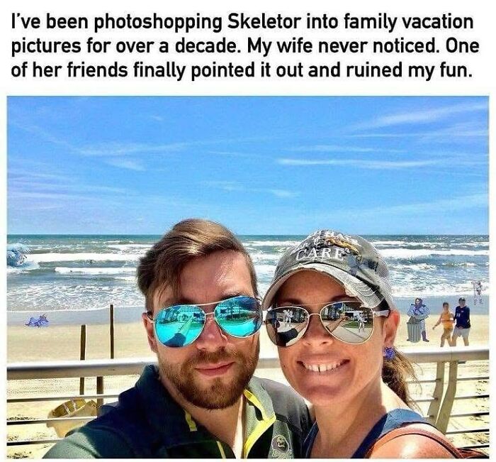 Couple smiling for a beach selfie with a hidden photoshopped Skeletor figure in the background, adding random meme chaos.