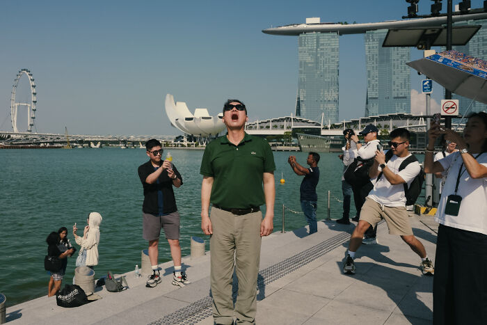 Man in green shirt captured in a poetic, cinematic image with tourists and waterfront cityscape in the background.