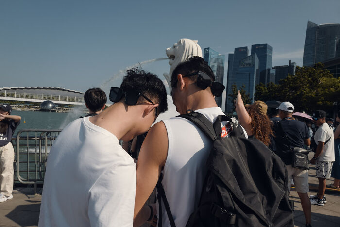 Two men with backpacks near waterfront and cityscape, capturing ordinary moments in poetic, cinematic photography style.