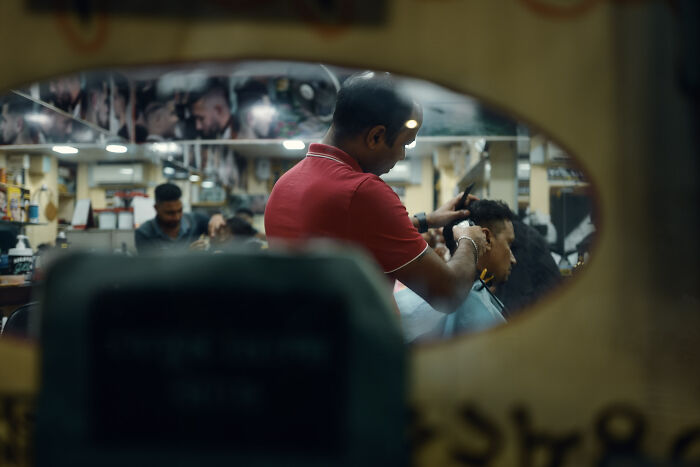 Photographer capturing ordinary moments in a barber shop, creating poetic and cinematic images with natural light and emotion.