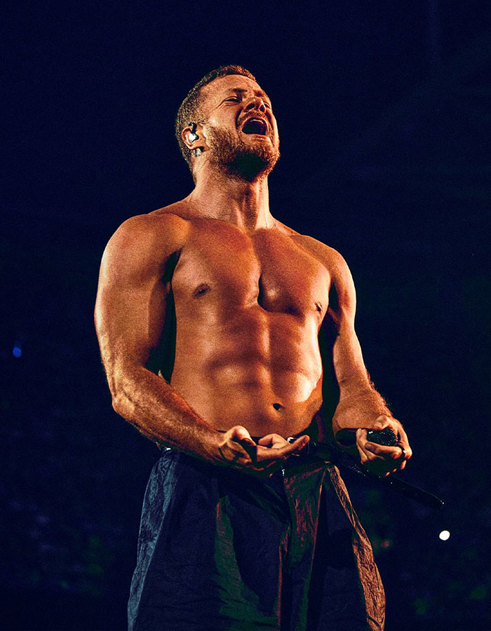 Dan Reynolds shirtless on stage during a live performance, highlighting themes of toxic masculinity and self-expression.