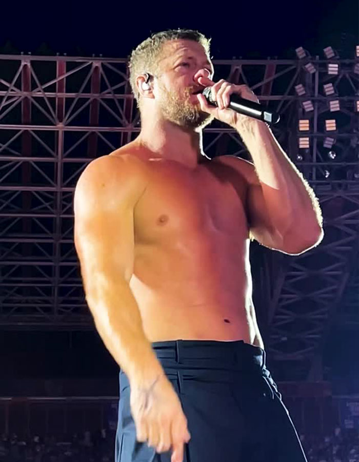 Dan Reynolds shirtless on stage, holding a microphone, highlighting issues around toxic masculinity in performance.
