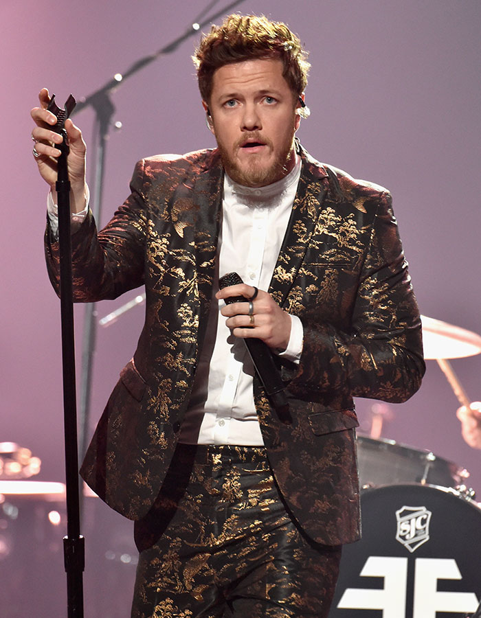 Dan Reynolds performing on stage in a patterned suit, highlighting themes related to toxic masculinity in music.