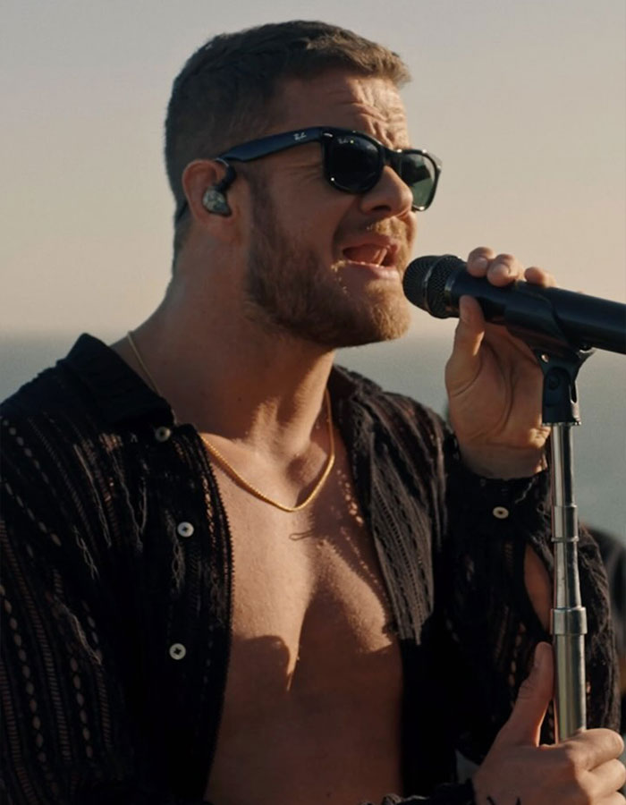 Dan Reynolds shirtless on stage singing into a microphone, wearing sunglasses, linking to toxic masculinity discussion.