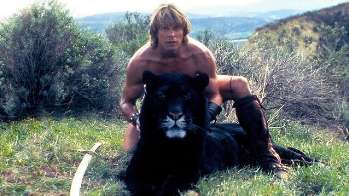 Man in medieval attire sitting behind a black panther in nature, illustrating videos with hidden context. - 6