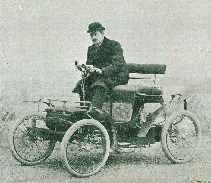 Early 1900s vintage car with a man in a suit and bowler hat, showcasing how wild the first cars really were.