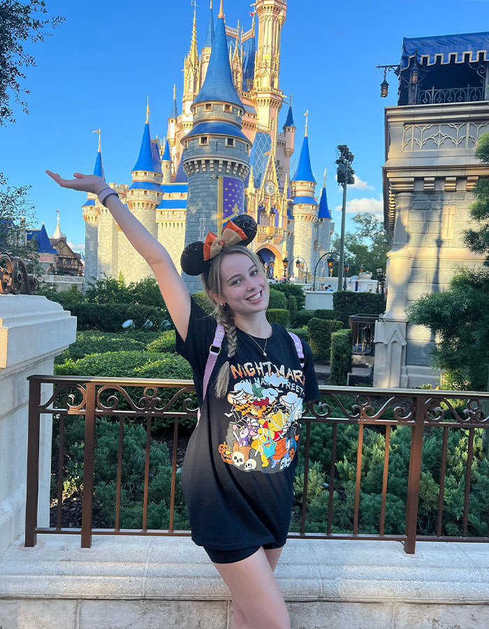 Young woman wearing Minnie Mouse ears poses happily in front of Disney World castle amid shocking twist in violent Disney World incident.