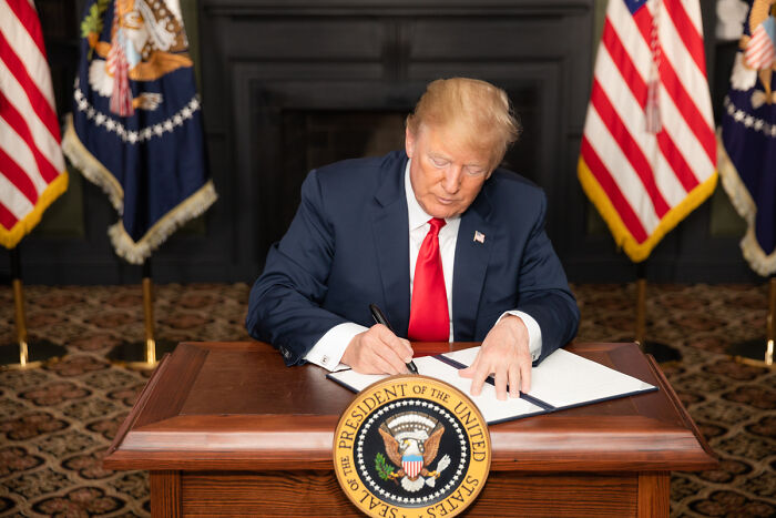 Former president signing a document at a desk with US flags in the background illustrating headlines that rocked the world