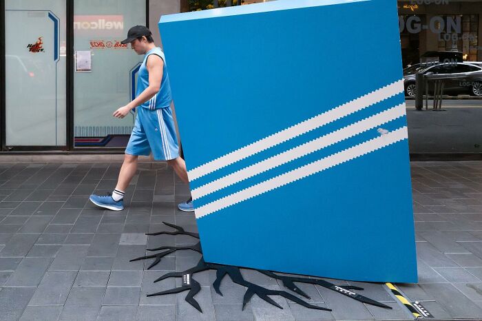 Man in blue sportswear walking past street art creating a street coincidence illusion of a c*****d pavement.