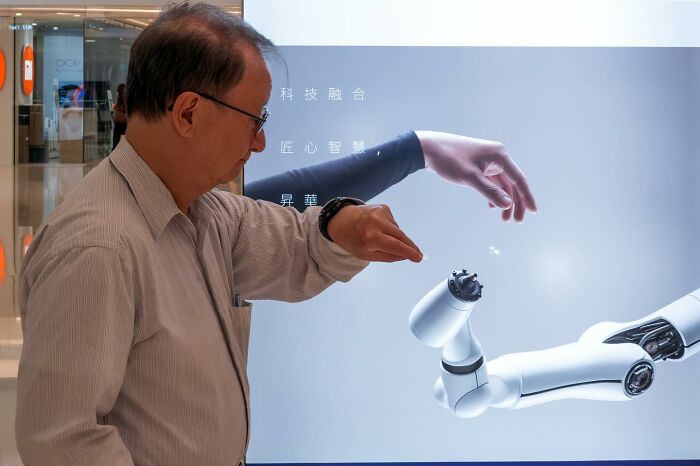 Man mimicking a robotic arm in a modern exhibit, illustrating unbelievable street coincidences caught on camera moments.