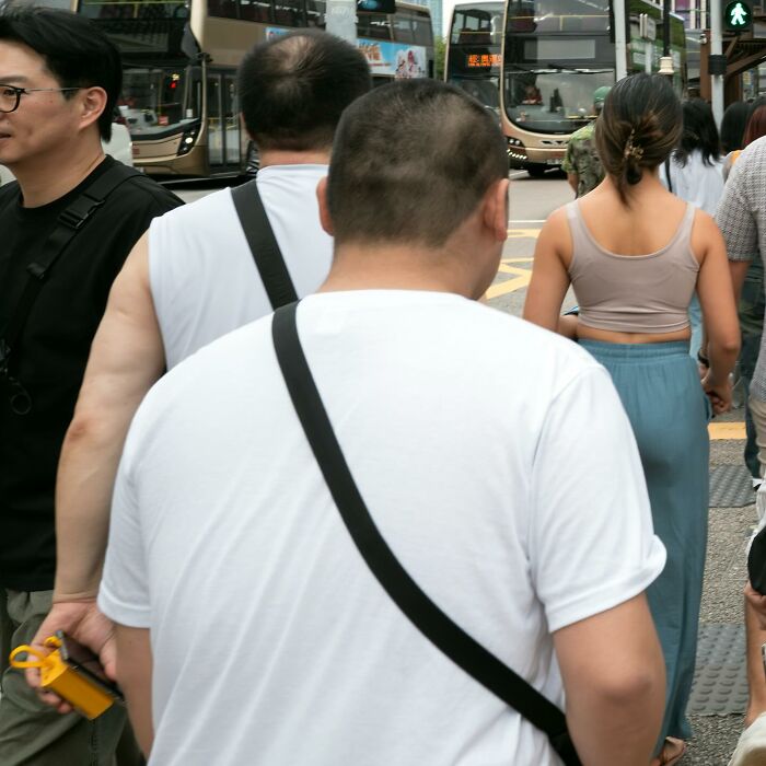 Crowded urban street scene with people walking and buses in the background capturing street coincidences.