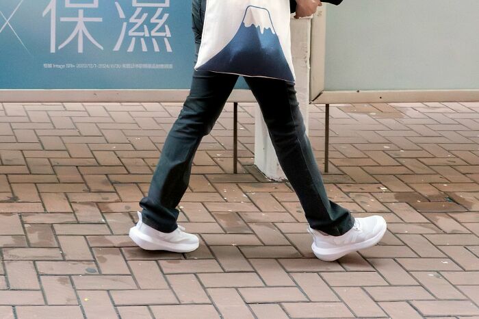 Person walking on brick street wearing black pants and white sneakers in an urban street coincidence moment.