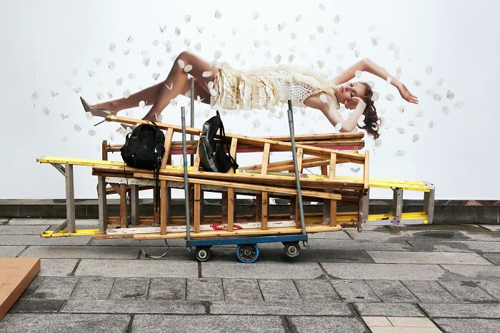 Woman seemingly floating above stacked ladders and backpacks on a street, capturing unbelievable street coincidences caught on camera.