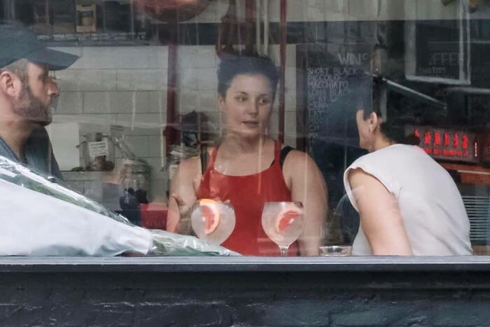 Three people sitting inside a cafe with drinks, captured as part of unbelievable street coincidences caught on camera.