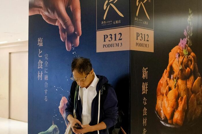 Man standing by a wall with an image of a hand sprinkling salt, showcasing street coincidences caught on camera.