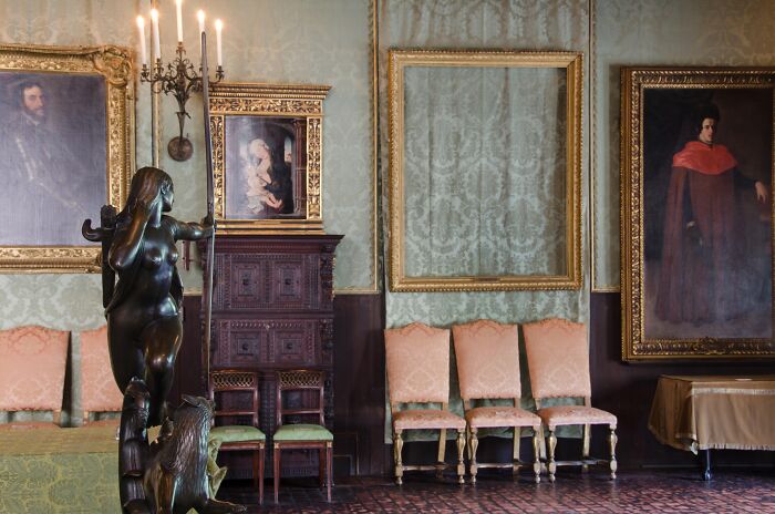 Ornate vintage room with antique chairs, framed portraits, and a mysterious statue as part of baffling unsolved mysteries.