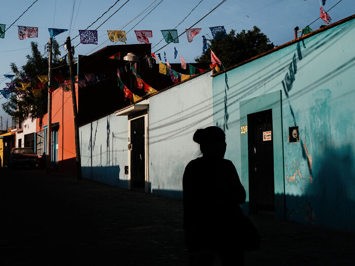 Silhouette of a person walking past colorful buildings with festive street photography capturing everyday life.