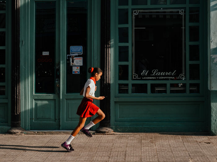 Young girl in red skirt running along a sidewalk in street photography capturing life as it really is.