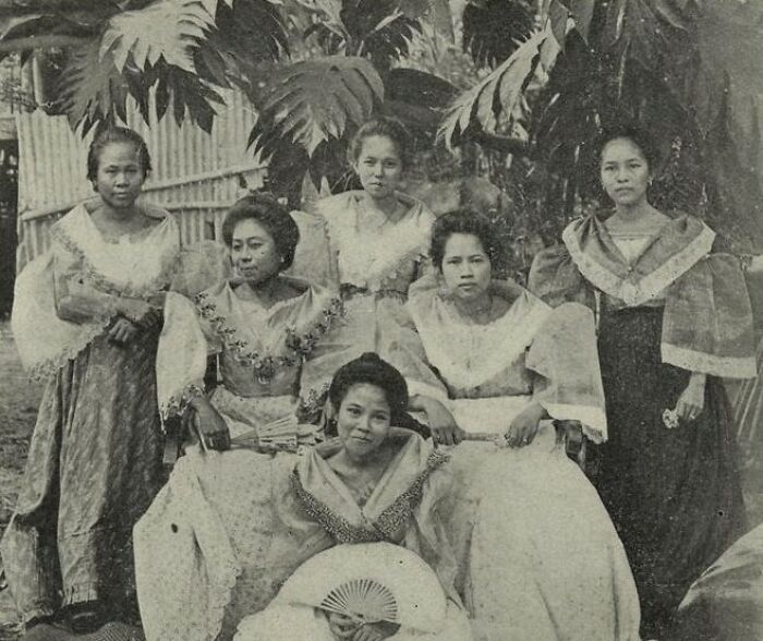 Group of Filipino women in traditional dresses posing outdoors in the Philippines during the 1890s era.