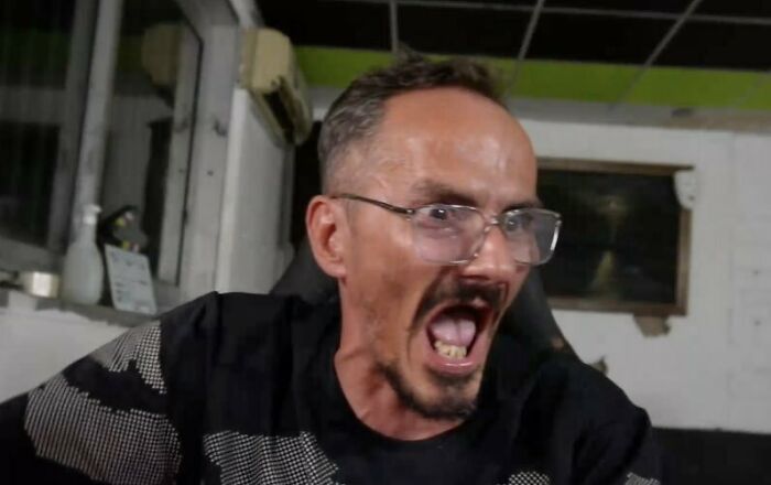 A distressed male streamer wearing glasses in a room, reacting intensely during a live broadcast. A distressed male streamer wearing glasses in a room, reacting intensely during a live broadcast.