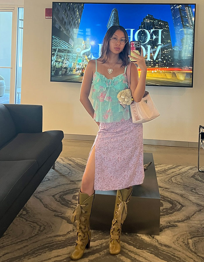 Gen Z worker posing in trendy office attire with floral top, pink skirt, and brown lace-up boots supporting workplace dress code debate.