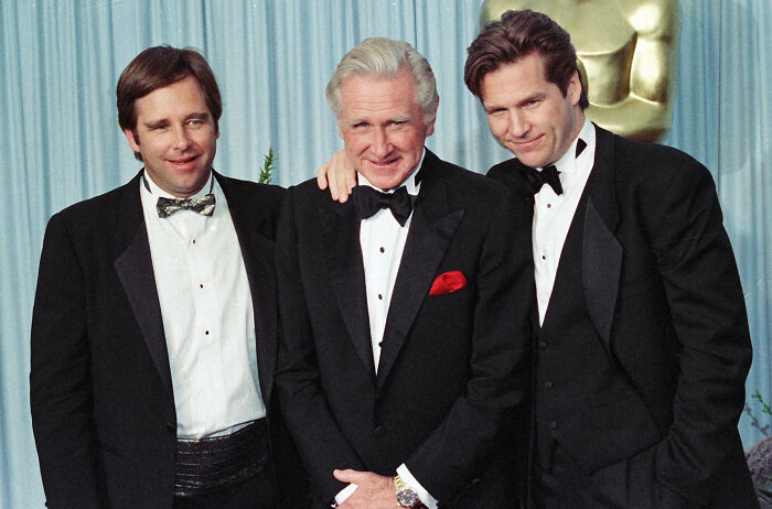 Three generations of a legendary entertainment family dressed in tuxedos at a formal awards event, posing together.