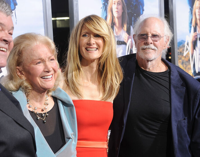 Three generations of a legendary entertainment family smiling together at a red carpet event, showcasing family legacy.