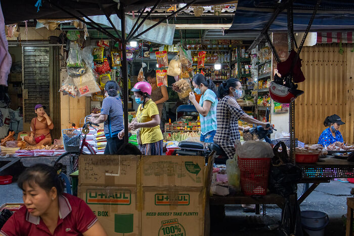 Busy street market scene with locals wearing masks, showcasing cultural life captured by a photographer in over 50 countries.