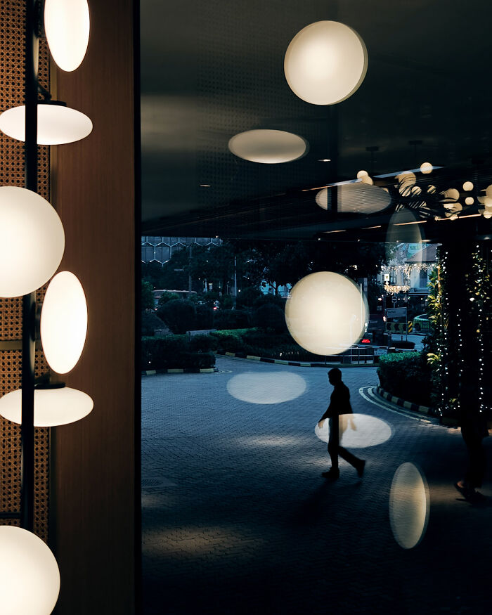 Silhouetted person walking at night with illuminated orbs, showcasing poetic cinematic photography and ordinary moments transformed.