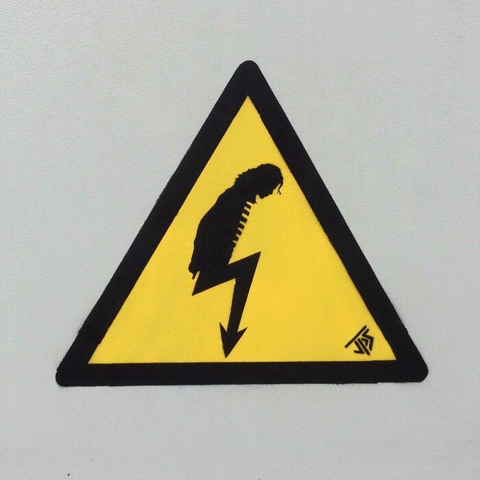 Graffiti street art showing a yellow warning sign creatively altered to depict an electric shock with a person silhouette.