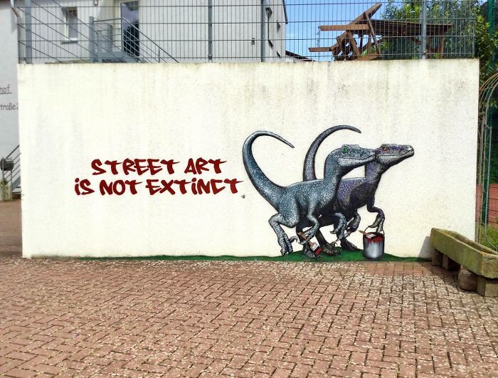 Graffiti street art with two velociraptors painting on a wall, creatively interacting with the surrounding environment.