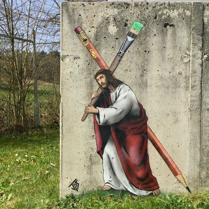 Graffiti art interacting with surroundings shows a figure carrying oversized pencils painted on a concrete wall outdoors.