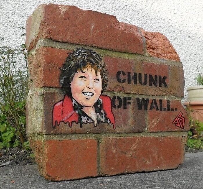 Graffiti street art on a broken brick titled chunk of wall featuring a smiling person and creative stencil design.