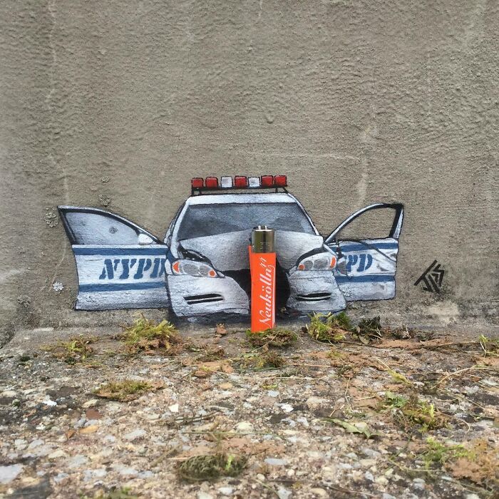 Graffiti of a police car with open doors cleverly interacting with a lighter placed as the car's front grill on a street wall.